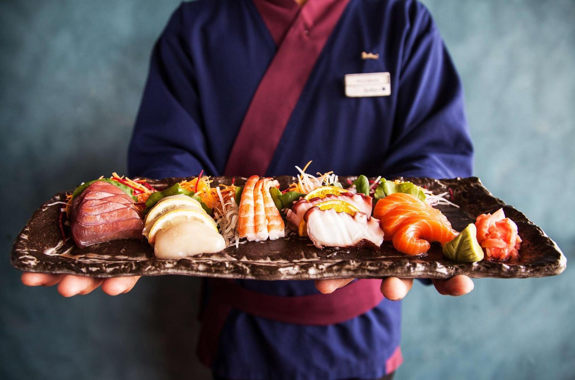 Radisson Blu Hotel, Dubai Deira Creek Exterior photo A sushi chef holding a plate of sushi